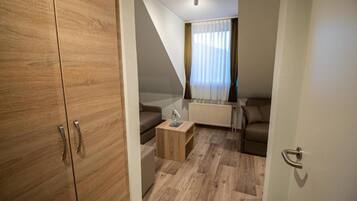 A modern room with a wooden wardrobe, a sofa, a small wooden table, and a radiator.