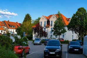 Un quartier résidentiel avec des voitures garées, un immeuble avec un toit rouge et des arbres.