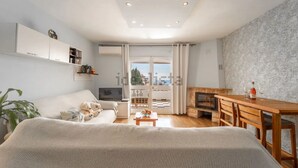 Una sala de estar moderna con sofá, mesa de comedor, chimenea y balcón con vistas.
