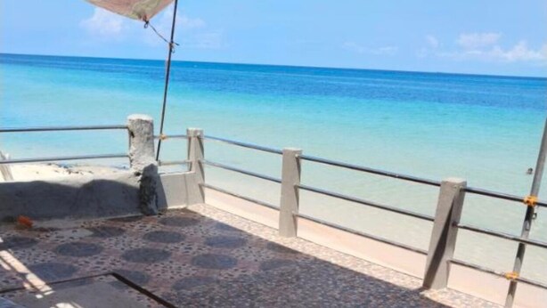 A beachside terrace with a railing, a concrete floor, and a view of the ocean.