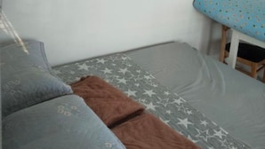 A room with a bed, a sofa, a small table, and a chair.