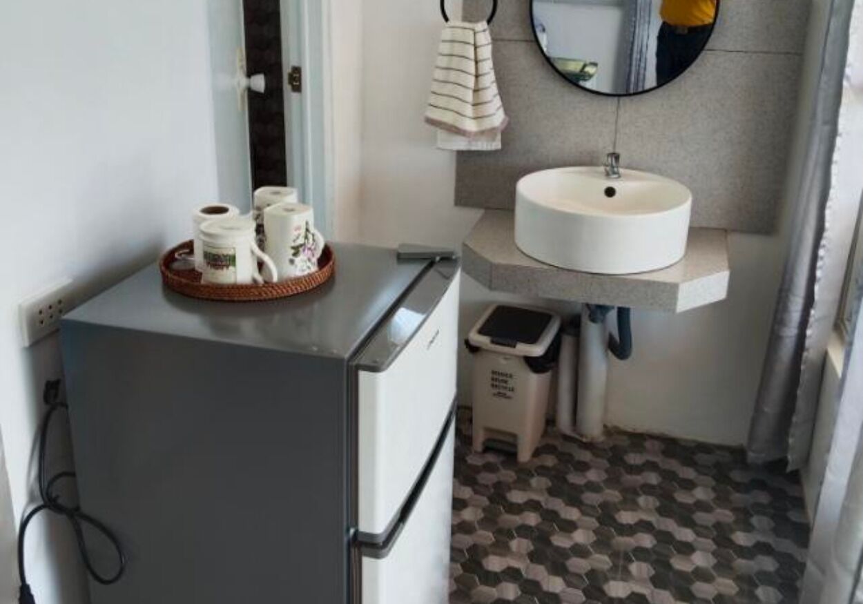 Una kitchenette compacta con refrigerador, pileta y basurero.