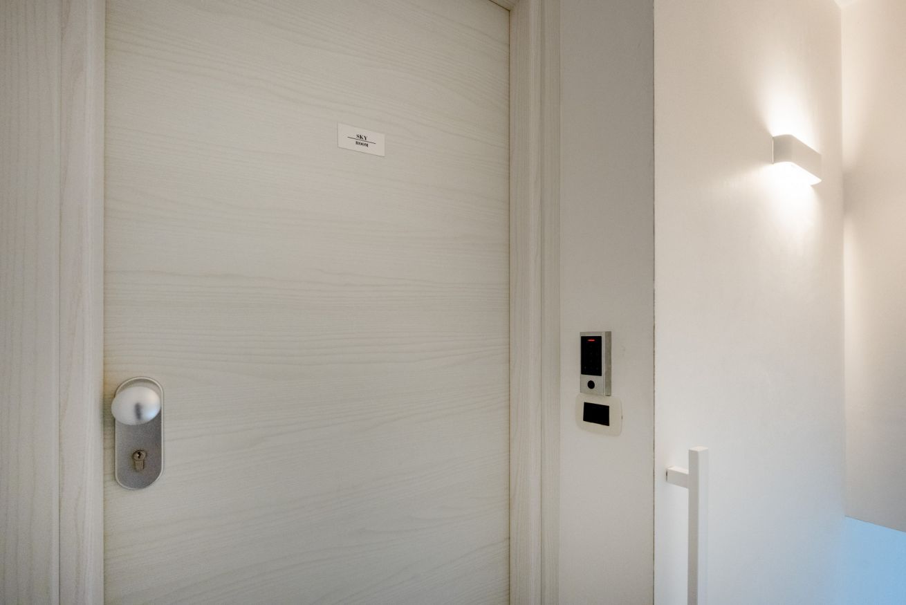 Une porte blanche avec une serrure et une plaque portant l’inscription « Sky Room ».