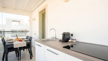 A modern kitchen with a black countertop, white cabinets, a sink, and a coffee maker.