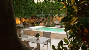 Ein Poolbereich mit Tisch und Stühlen, umgeben von Pflanzen und Grünwerk.