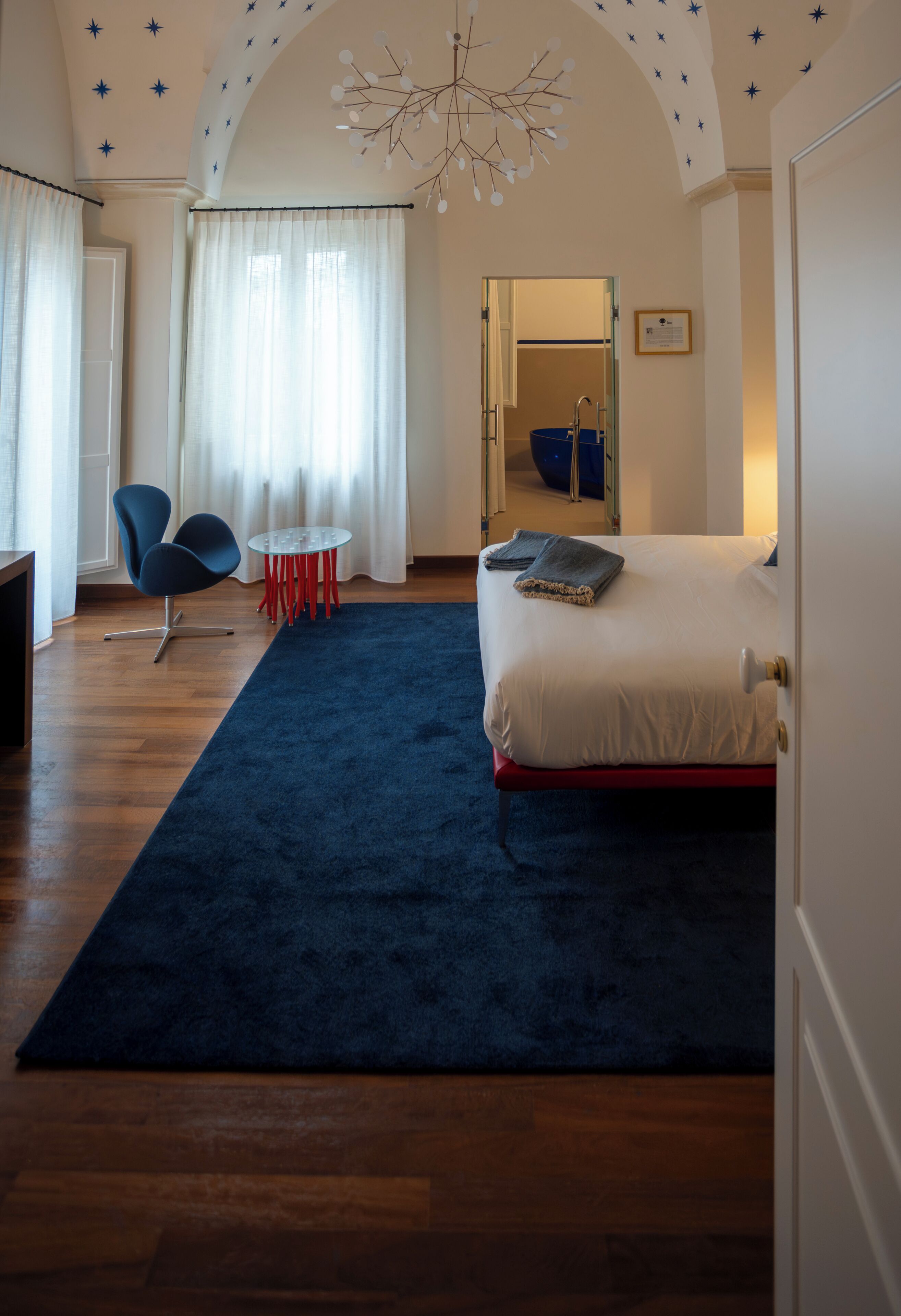 A bedroom with a bed, a chair, a table, and a mirror.