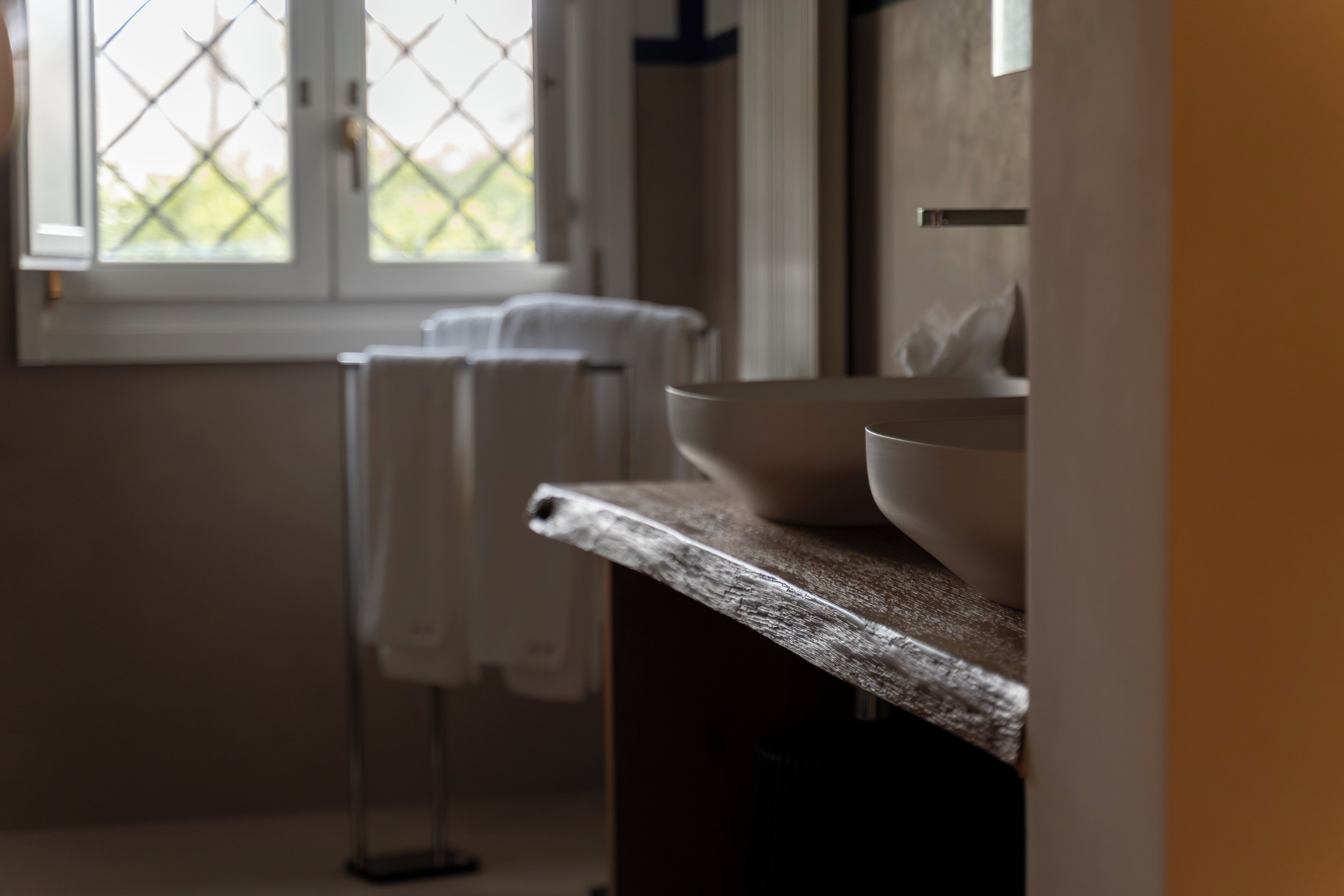 Ein Badezimmer mit Waschbecken, Spiegel und einem Fenster mit Blick auf Grünflächen.