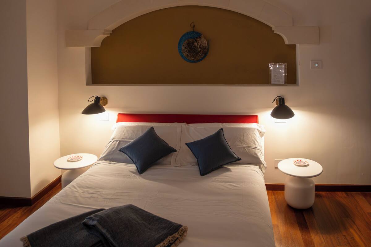 Ein Schlafzimmer mit Bett, Nachttischen, einer Chandelierleuchtre und einer Zierte Decke.