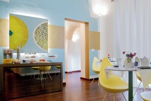 A modern kitchen with a dining area, featuring a wooden floor, yellow chairs, and a table set for dining. - Rose Iconic Rooms (Lecce)
