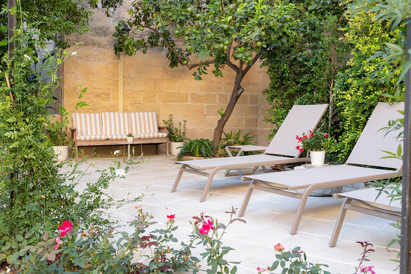 Eine Terrasse mit Lounge-Möbeln, einer Bank und Pflanzen in Töpfen.