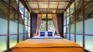 Une chambre dotée d’un grand lit, d’un plancher en bois et de grandes fenêtres avec des rideaux.