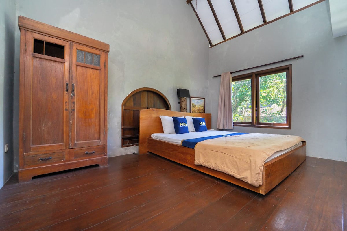 Un dormitorio con cama de madera, armario, ventana con vistas y tragaluz.