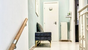 A staircase with a handrail, a bench, a door with a nameplate, and a radiator. - Casa Letizia - Assisi (Tordandrea)
