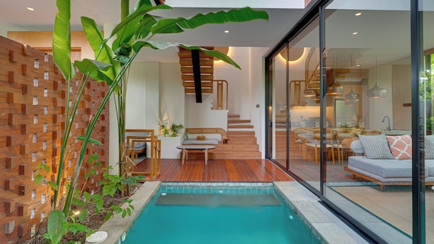 Un interior moderno con piscina, suelo de madera y una escalera que conduce a un comedor.