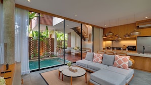 Un moderno salón con un sofá, una mesa de centro y vista a una piscina.