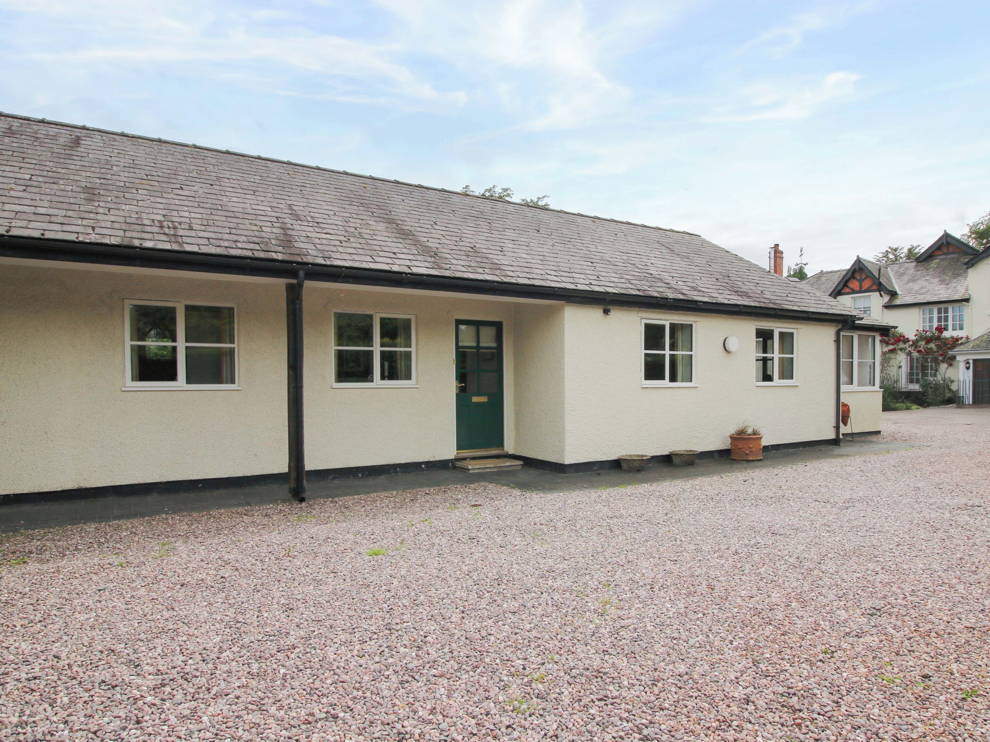 A single-story building with a flat roof, a green door, and multiple windows.