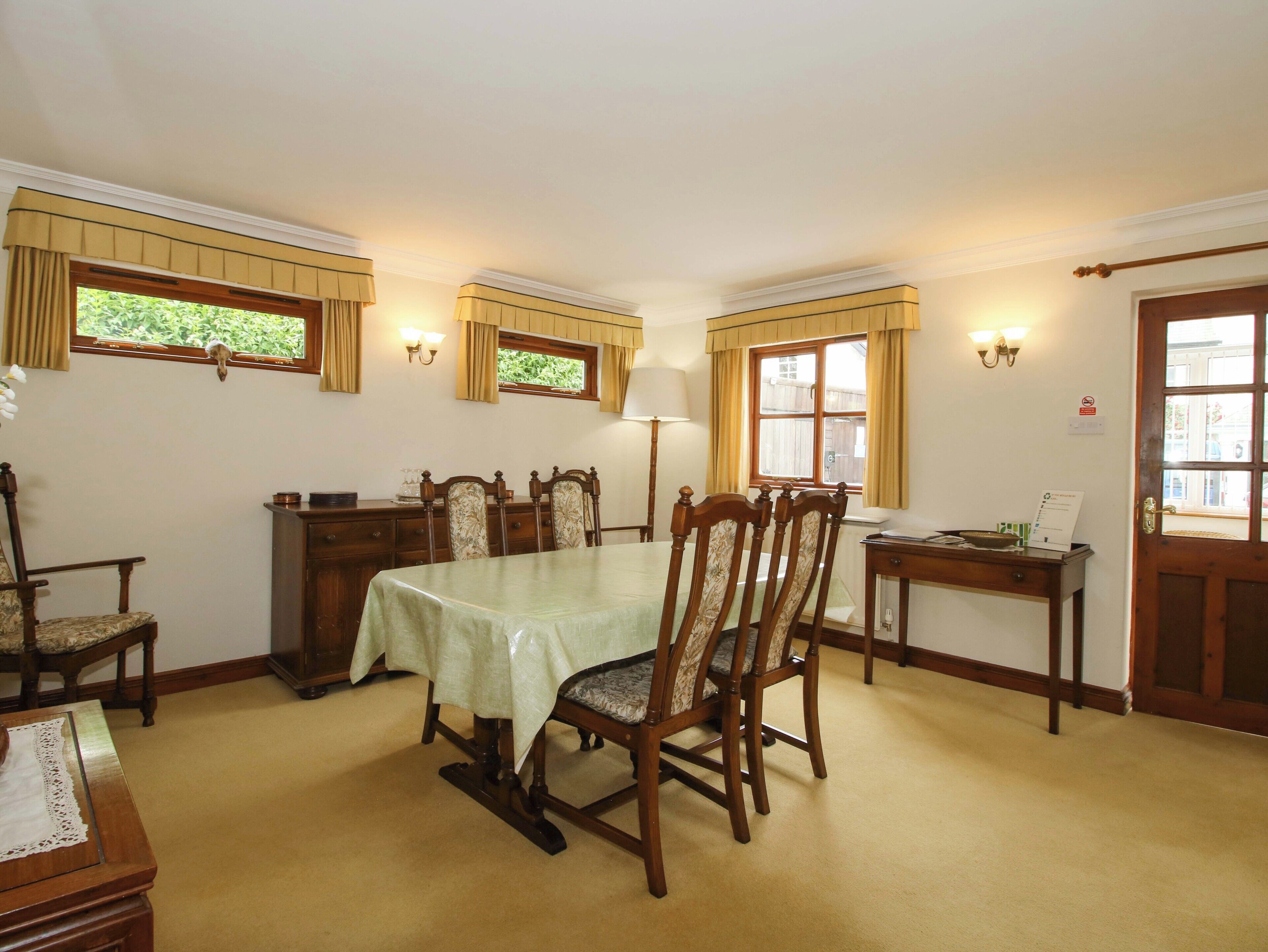 A dining room with a table, chairs, a lamp, and a door.