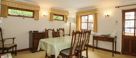 A dining room with a table, chairs, a lamp, and a door.