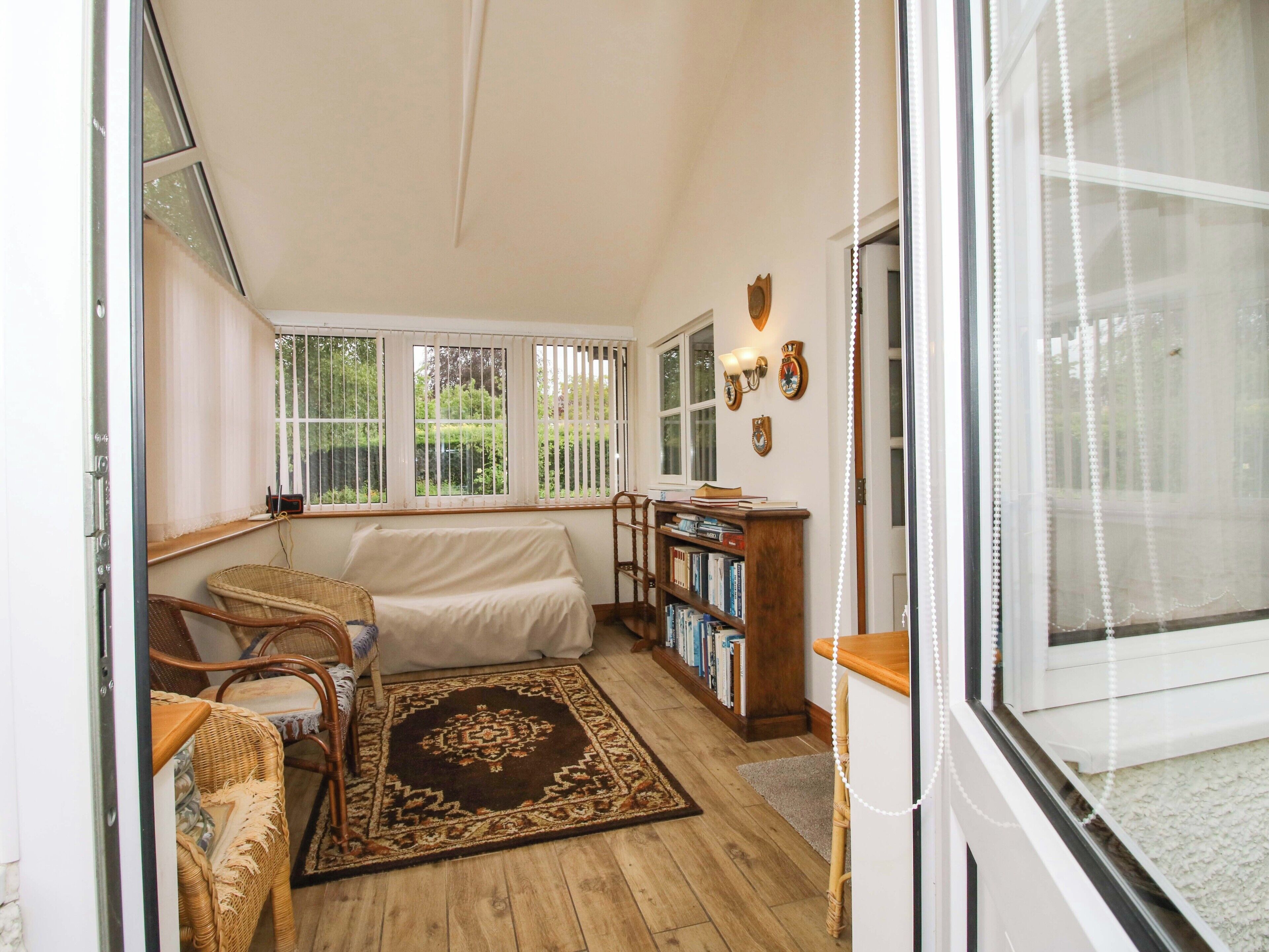 A cozy room with a sofa, a wooden bookshelf, and a window with a view of greenery.