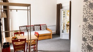 A room with a bed, a table with chairs, a wardrobe, and a door leading to another room.