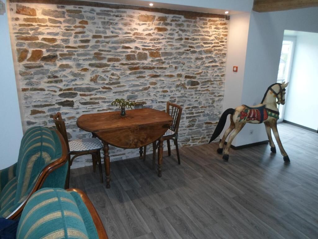 Un coin repas agrémenté d’un mur en pierre, d’une table en bois, de chaises et d’une statue de cheval décorative.