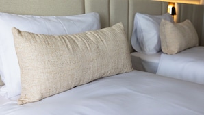 Une chambre d’hôtel avec un lit, des oreillers et une tête de lit.