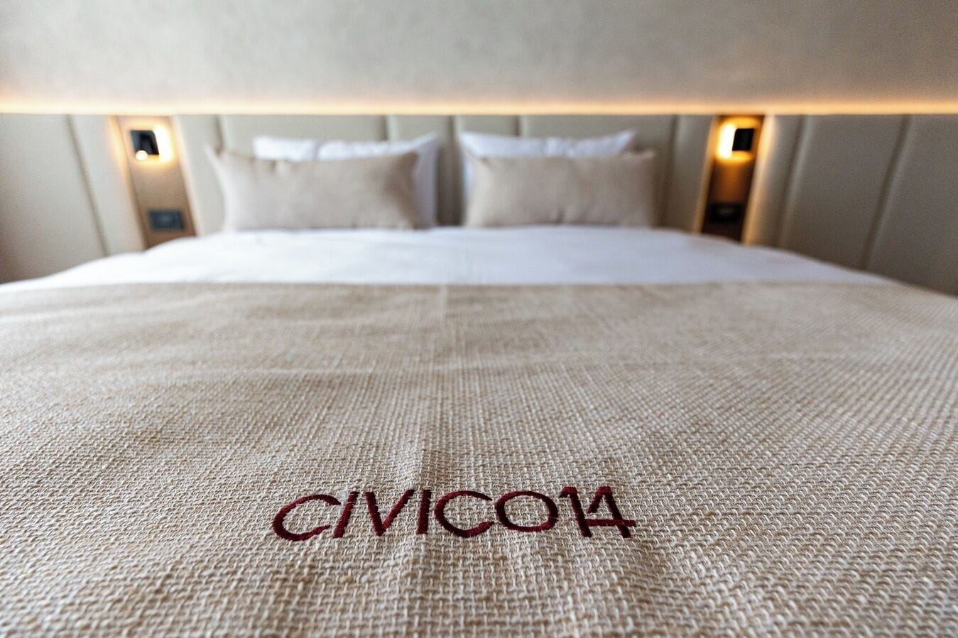 Un letto con una testiera, cuscini e una coperta con ricami.