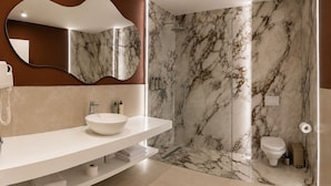 Une salle de bain moderne avec une douche en marbre, un grand miroir et un meuble-lavabo blanc.