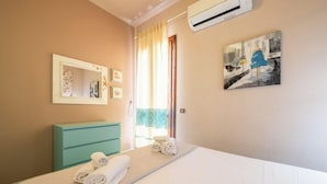 A hotel room with a bed, a bathroom counter, a mirror, and a painting on the wall.