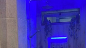 Ein modernes Badezimmer mit Dusche, einem Holzkosmetikschrank und einem Regal mit Flaschen.