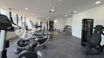 Un gimnasio con cintas de correr, elípticas y equipo de levantamiento de pesas.