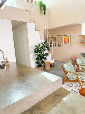 Eine moderne Küche mit Marmorarbeitsplatte, eine Treppe mit geometrischem Design und ein Essbereich mit gemusterten Stühlen.