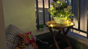 Ein Balkon mit einem Blumentopf, einem karierten Kissen und Snacks.