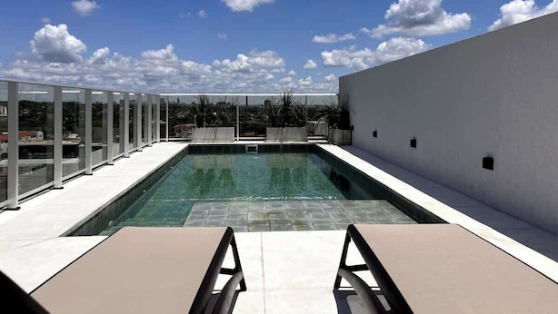 Une piscine sur le toit, avec un ciel dégagé et des bâtiments qui se dressent au loin.