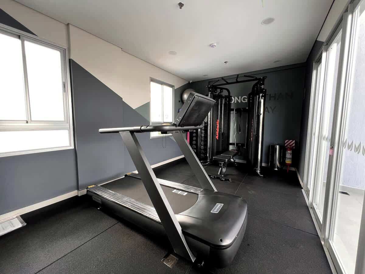 A gym with treadmills, weight machines, and a mirrored wall.