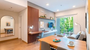Un intérieur moderne avec une table à manger en bois, un canapé, un téléviseur et une fenêtre donnant sur un paysage verdoyant.