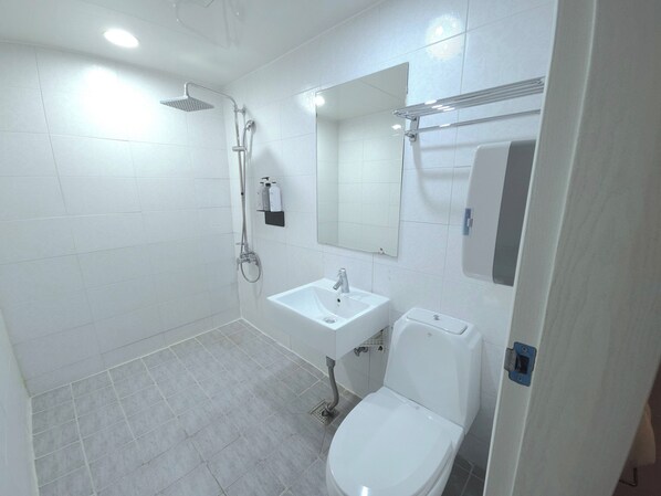 A modern bathroom with a shower, sink, toilet, and a mirror.