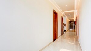 A modern hotel corridor with a polished floor, wooden doors, and recessed lighting. - Super Townhouse Taj Nagri Phase 2 (Agra)