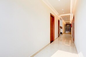 Un pasillo moderno de hotel con piso pulido, puertas de madera e iluminación empotrada.