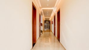 A hotel corridor with a polished floor, wooden doors, and recessed lighting. - Super Townhouse Taj Nagri Phase 2 (Agra)