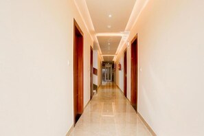 Pasillo de hotel con piso pulido, puertas de madera e iluminación empotrada.