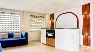 A reception area with a blue sofa, a reception desk labeled 'TOWNHOUSE,' and a patterned wall. - Super Townhouse Taj Nagri Phase 2 (Agra)