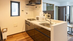 Eine moderne Küche mit integriertem Mikrowellenherd, Herd und Spüle, Holzboden und einem Fenster, das für natürliches Licht sorgt.