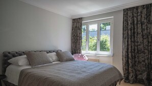 Un dormitorio con una cama grande, una ventana con cortinas y un radiador.