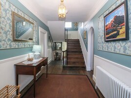 A hallway with patterned wallpaper, a wooden staircase, a radiator, and a framed painting.