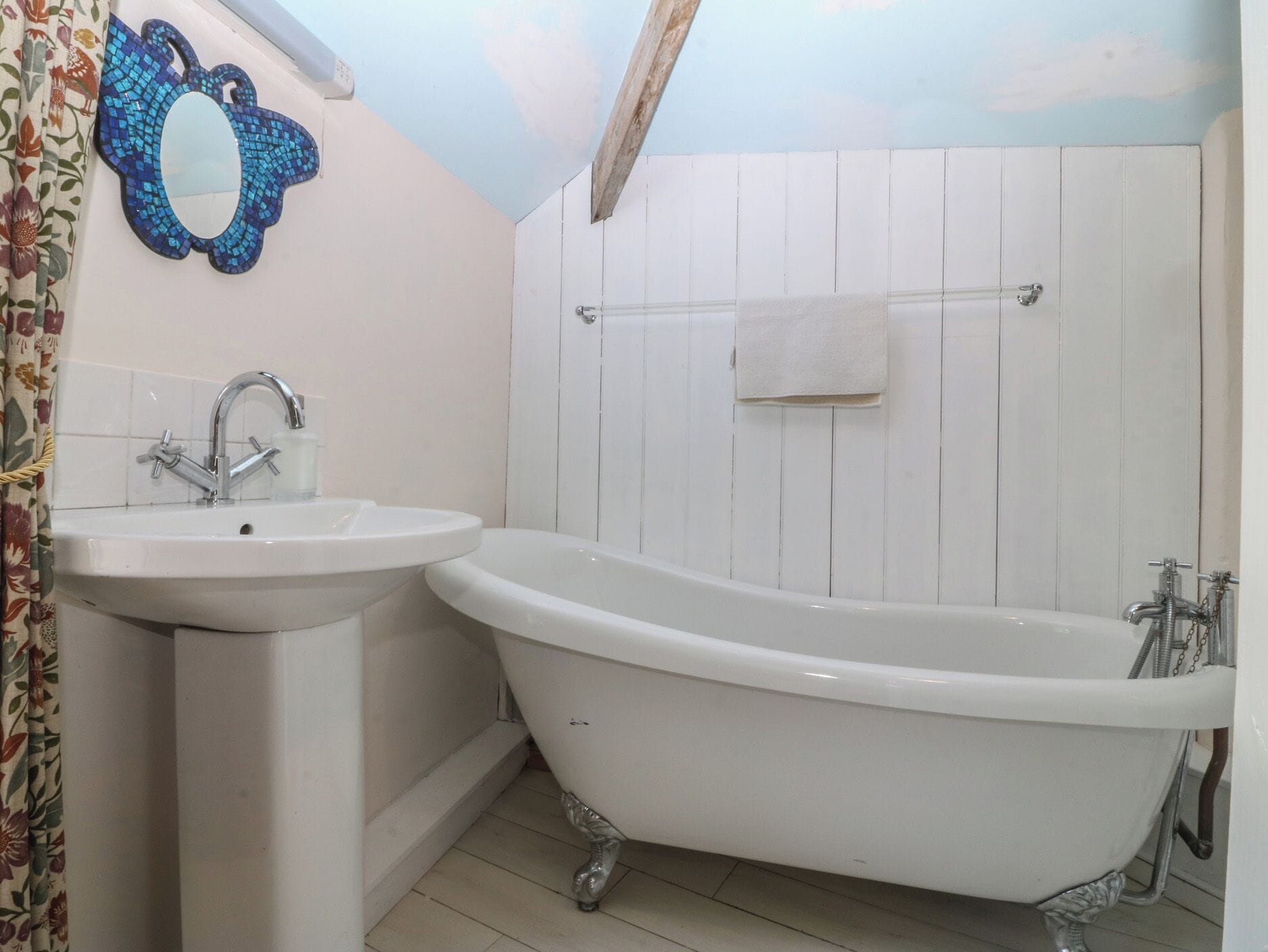 Un baño con lavamanos, bañera y un espejo decorativo.