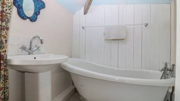 Un baño con lavamanos, bañera y un espejo decorativo.