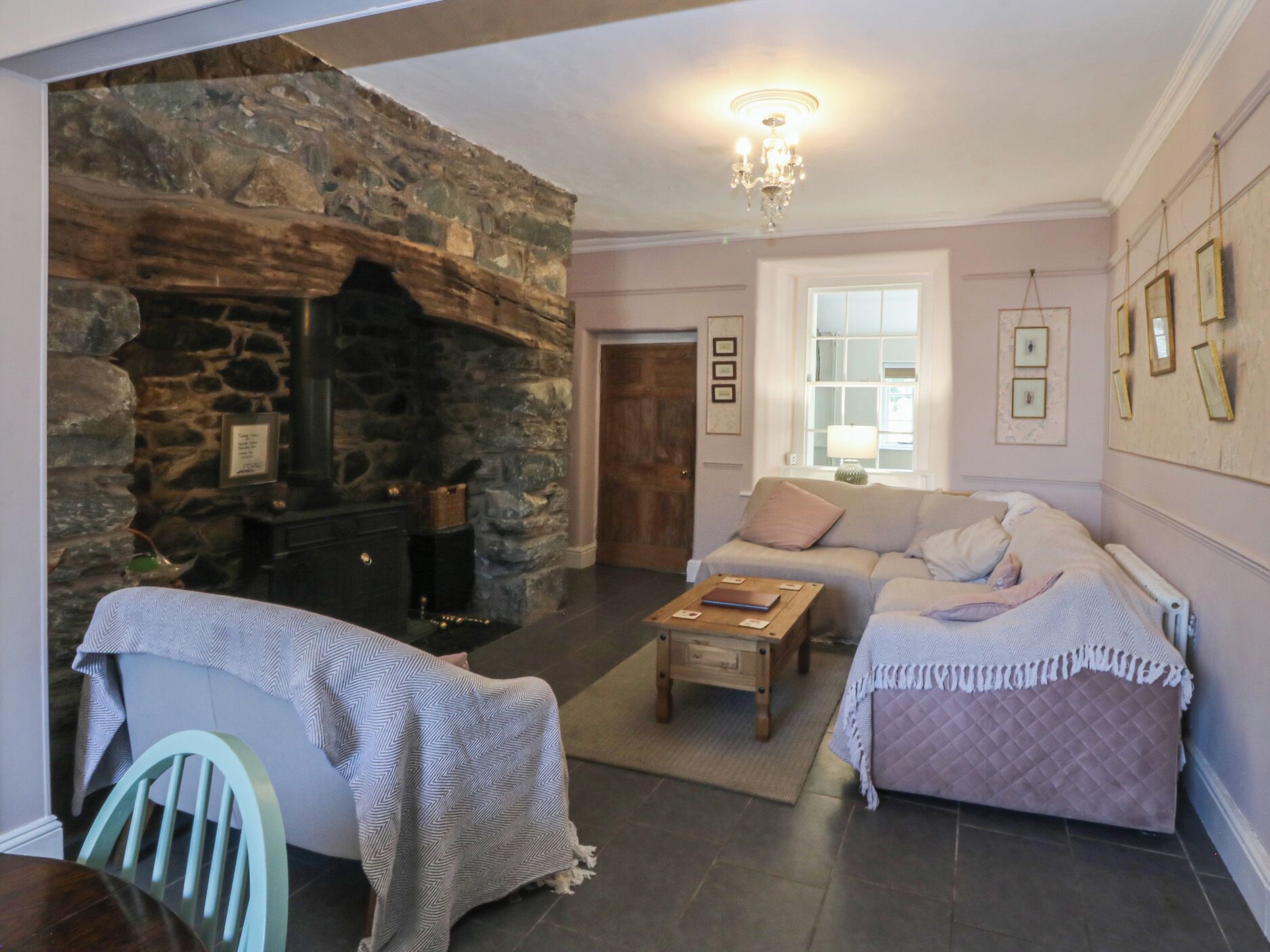 A cozy living room with a stone fireplace, a sofa, a coffee table, and a dining area with a chair.