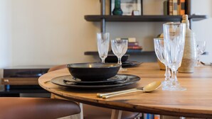Une table à manger avec un bol noir, deux verres à vin et une cuillère.