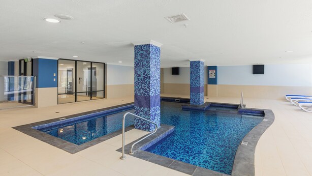 Une piscine intérieure avec des murs carrelés et une zone de baignade bien dégagée.